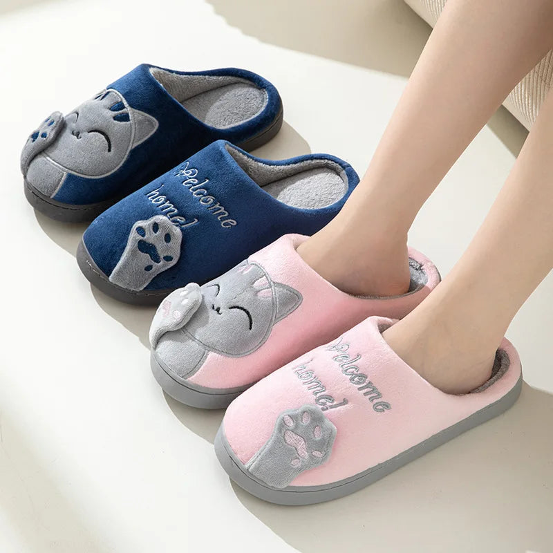 A person wears pink Happy Pawprints Lucky Cat Slippers by KittyNook Cat Co.; a blue pair is also shown.