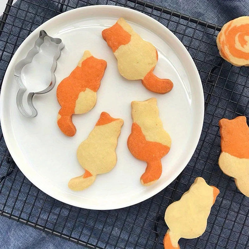 Cat-shaped orange and white cookies made with KittyNook Cat Co.'s Cat Shape Cookie Cutter Set on a cooling rack.