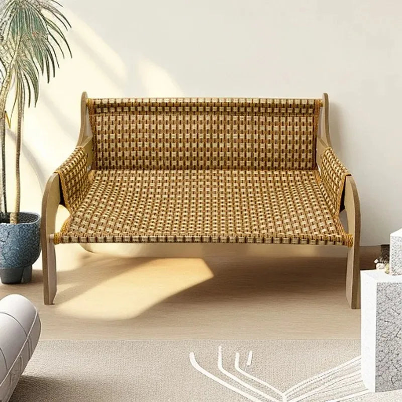 A woven rattan bench with wooden arms sits near a KittyNook Cat Co. Cat Summer Sofa Bed in a sunlit room.