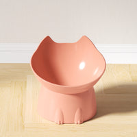 Thumbnail for The Orthopedic Raised Cat Feeder by KittyNook Cat Co. is pink, cat-shaped, and sits on a light wooden floor by a white wall.