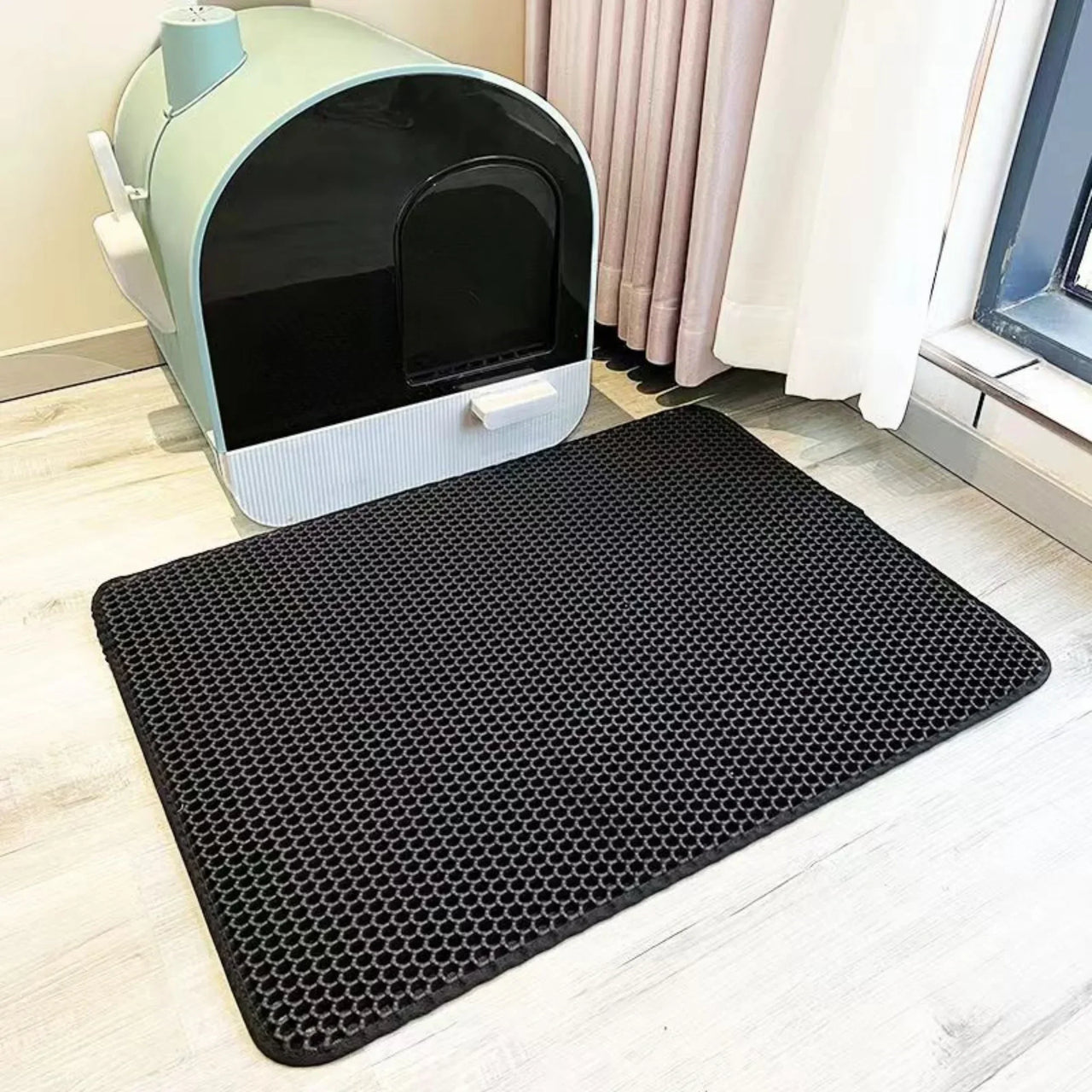 The KittyNook Cat Co. Non-Slip Dual Layer Litter Trapper is placed in front of a modern litter box by the window.
