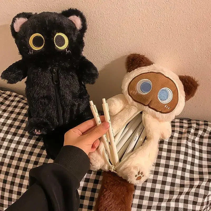 Two Kawaii Big-Eyed Cat Plush Pencil Cases by KittyNook Cat Co., black and cream, with pens in the cream case’s belly.