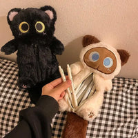 Thumbnail for Two Kawaii Big-Eyed Cat Plush Pencil Cases by KittyNook Cat Co., black and cream, with pens in the cream case’s belly.