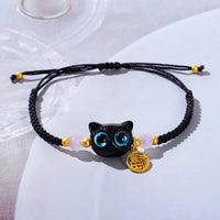 Thumbnail for KittyNook Cat Co. Lucky Charm Bracelet for Good Fortune—black braided with blue cat charm, pink beads, gold accents.