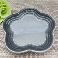 Thumbnail for Gray, flower-shaped KittyNook Cat Co. Extra Wide Raised Flower Cat Bowl on a mat, green faux flower in corner.