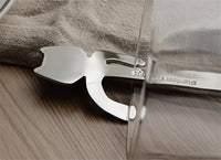 Thumbnail for The Cat Cling Stainless Steel Mug Spoon by KittyNook Cat Co. peeks out from under a glass on beige fabric over wood.