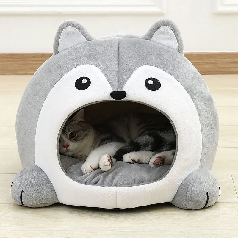 A gray and white cat relaxes in the KittyNook Cat Co. Fluffy Indoor Cat Cave Bed for Kittens on a wooden floor.