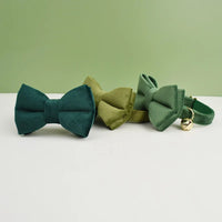 Thumbnail for Three green fabric bowties and a KittyNook Cat Co. Velvet Cat Collar with a gold bell on a white and green background.
